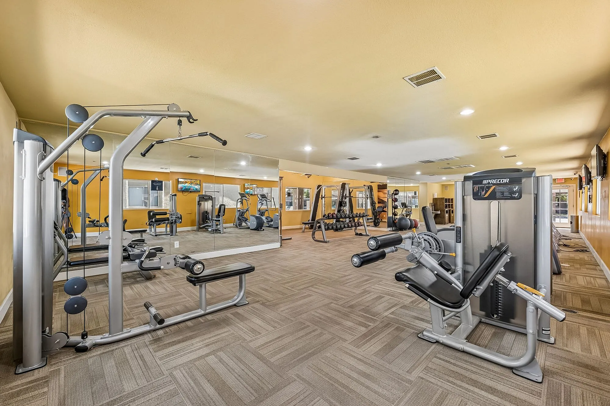 Bright and modern fitness center with a variety of exercise equipment and large mirrors, enhancing workout experiences at Camelot Apartments in Yuma, AZ.