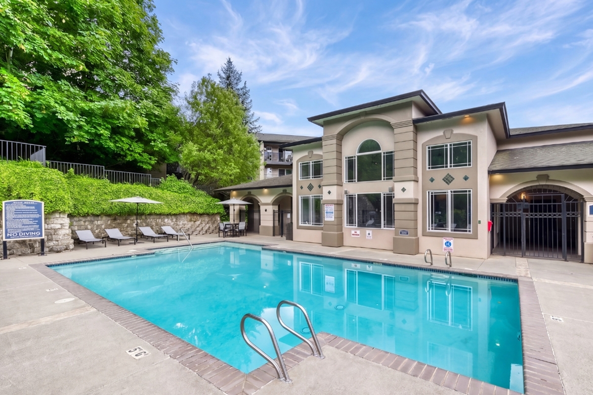 Elegant apartment exterior featuring a sparkling pool and lush greenery, perfect for relaxation and outdoor enjoyment.