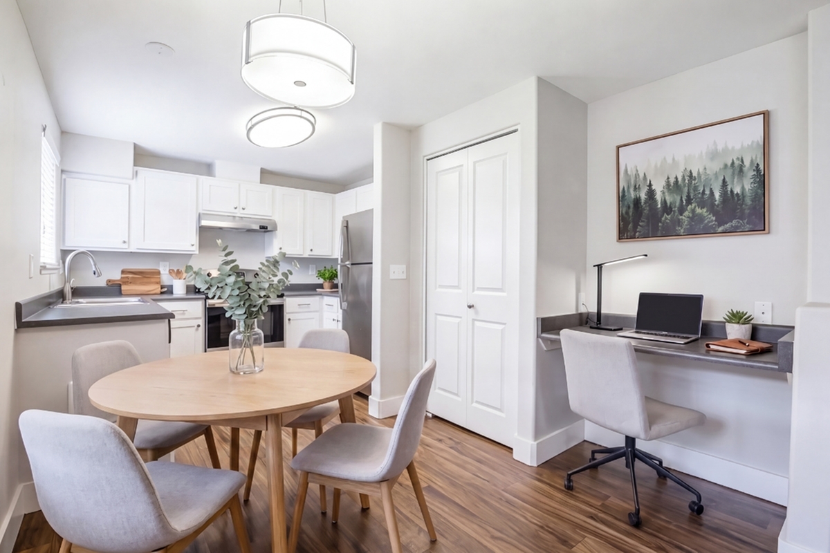 Modern kitchen and dining area with sleek white cabinetry, elegant lighting, and a cozy home office nook.