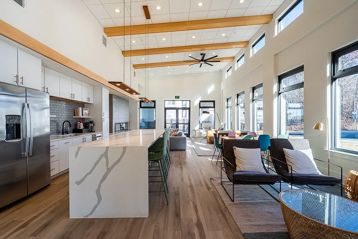 Bright and modern open-concept kitchen and clubroom area with high ceilings, sleek appliances, and abundant natural light at 5 Row Apartments in Charlottesville, Virginia.
