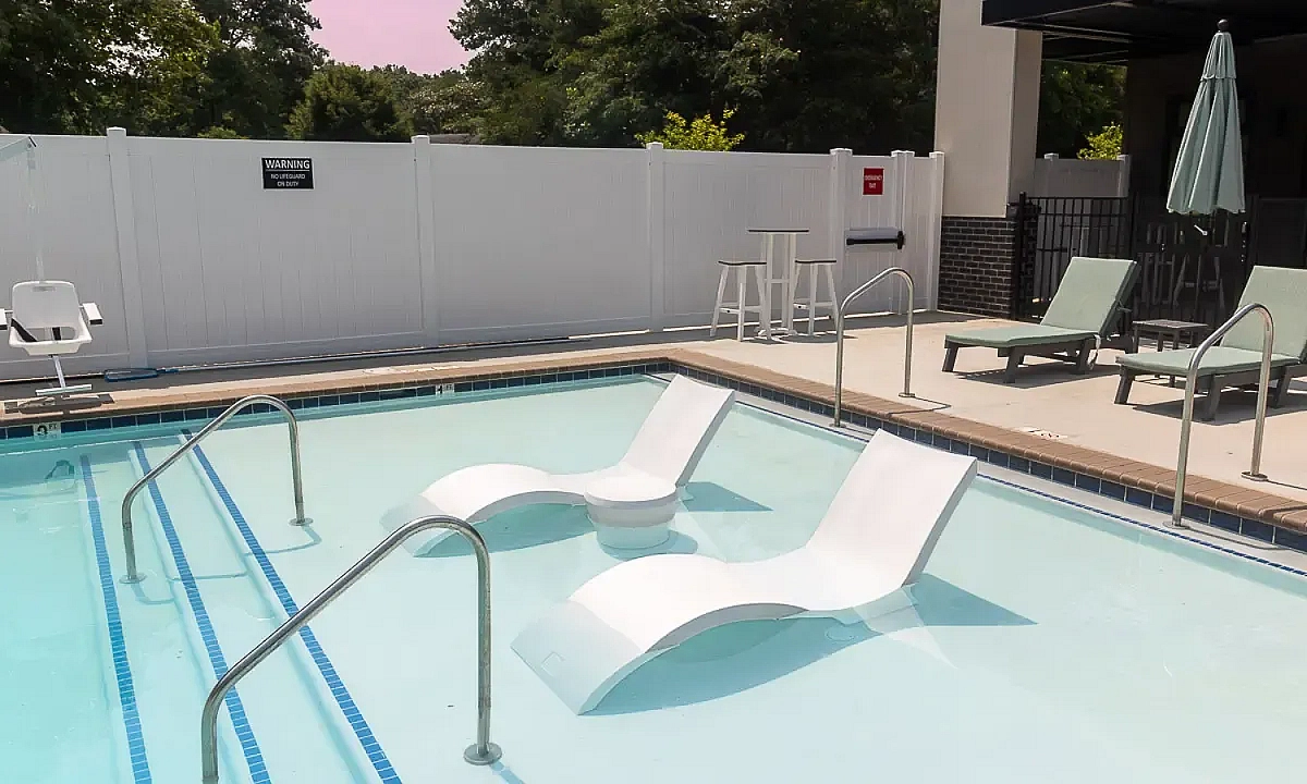 Luxurious apartment pool area with elegant lounge chairs, perfect for relaxation and leisure under the open sky at 5 Row Apartments in Charlottesville.