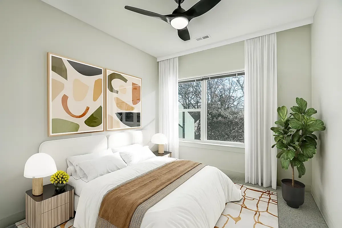 Bright and modern bedroom with a cozy bed, abstract art, and lush greenery, featuring large windows for ample natural light at 5 Row Apartments in Charlottesville.