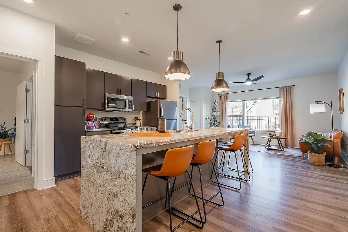 Modern open-plan kitchen and living area with sleek appliances, stylish pendant lighting, and large windows offering abundant natural light.