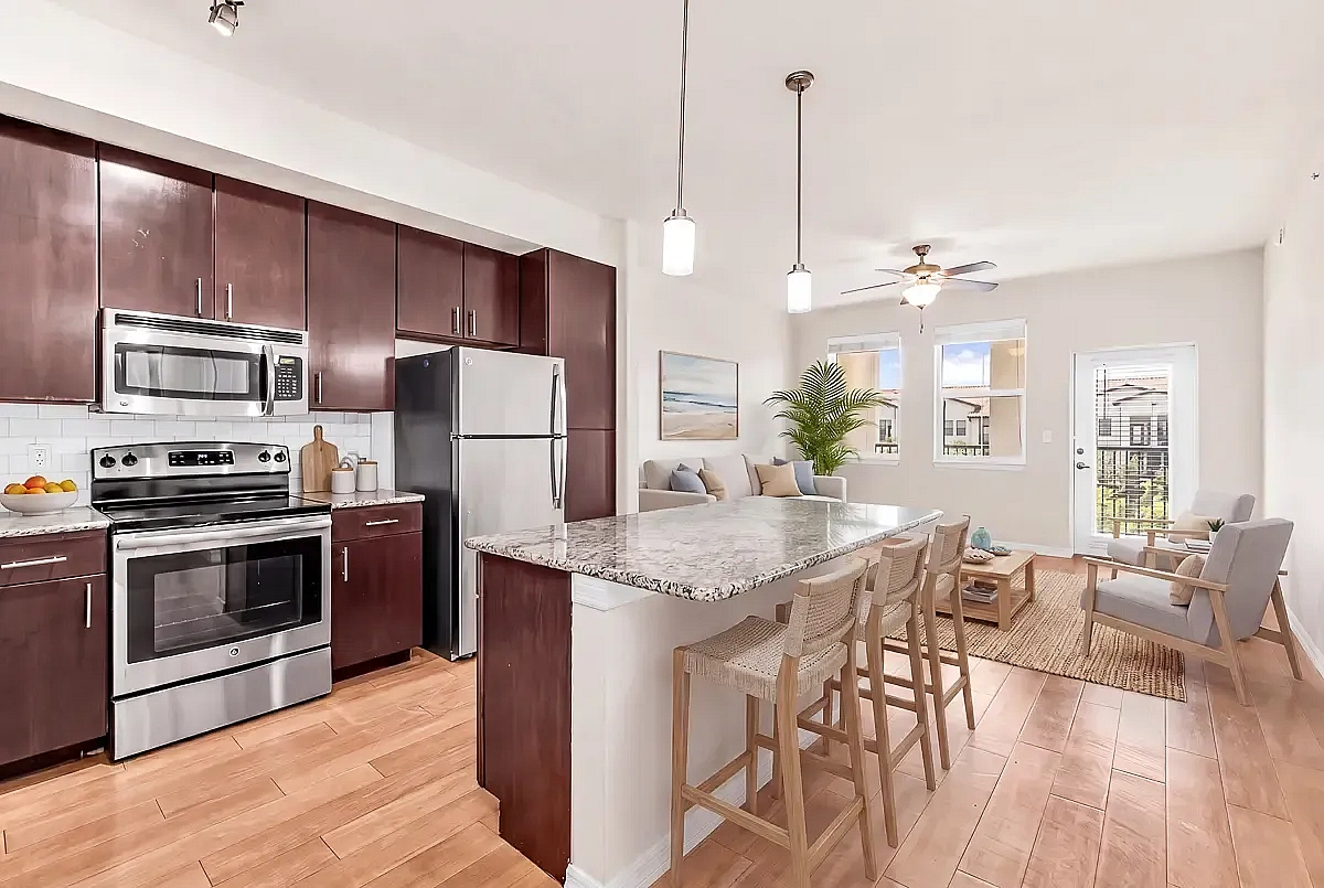 Modern kitchen and living space with elegant wood cabinetry, granite countertops, and abundant natural light, seamlessly merging comfort and style.