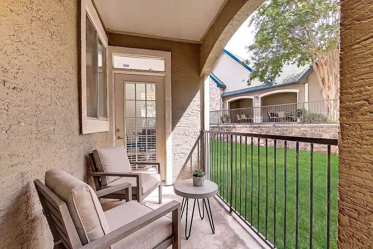 Charming apartment patio with cozy seating and a picturesque view of lush greenery.