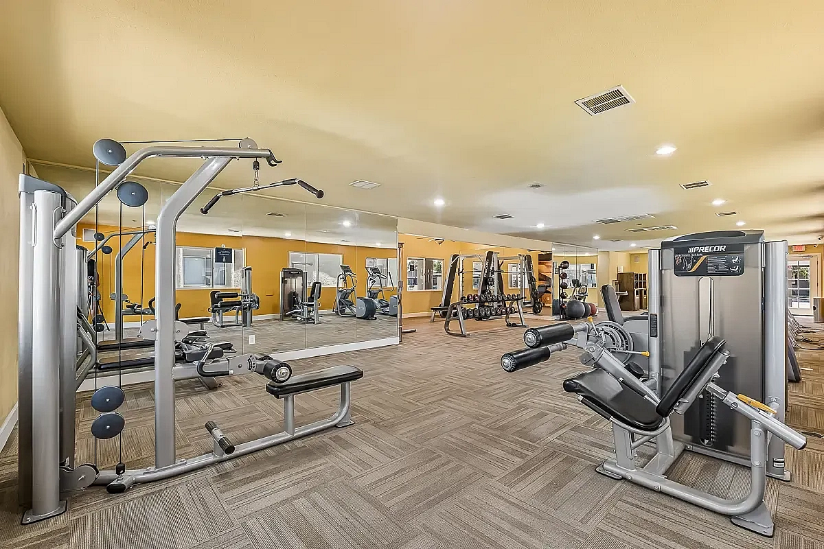 Bright and modern fitness center with a variety of exercise equipment and large mirrors, enhancing workout experiences at Camelot Apartments in Yuma, AZ.