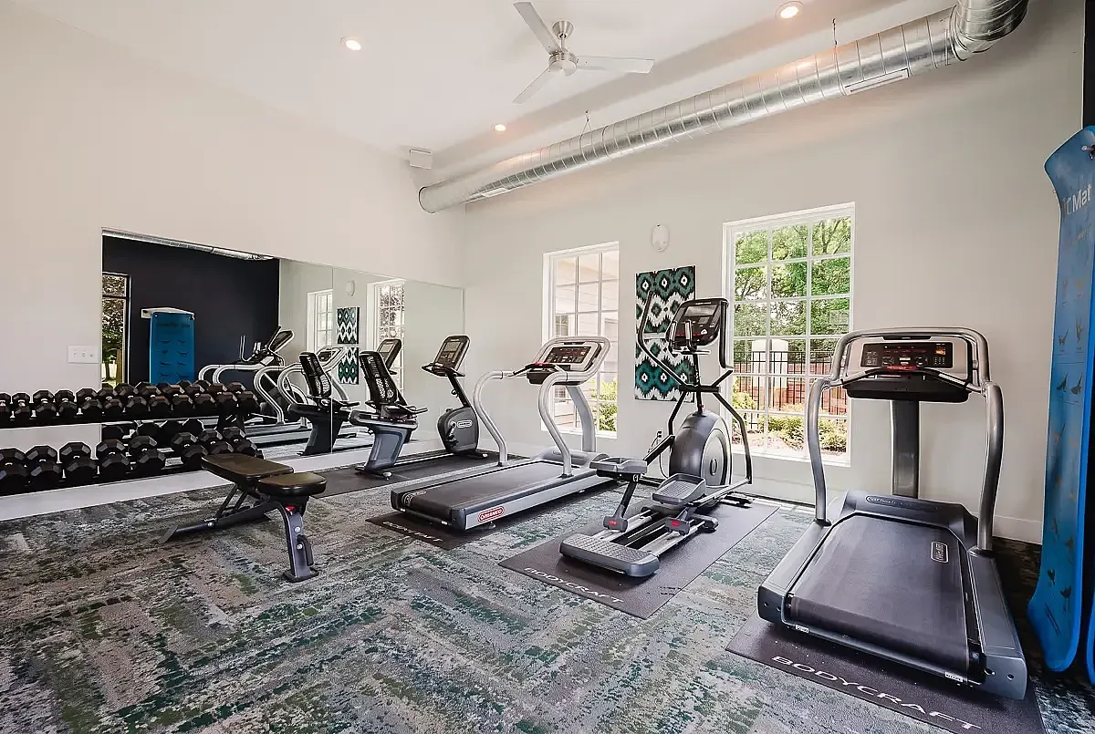 Modern fitness center at Alkire Glen Apartments with cardio machines, free weights, and a bright, open atmosphere.