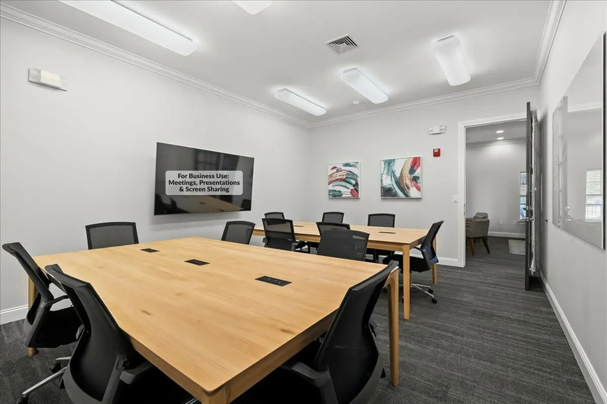 Modern conference room featuring sleek wooden tables, ergonomic chairs, and a large wall-mounted television, ideal for productive meetings.