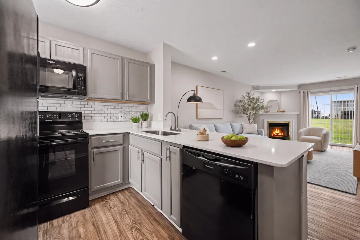 Modern open-concept kitchen and living room with elegant cabinetry, cozy fireplace, and natural light streaming through glass doors.