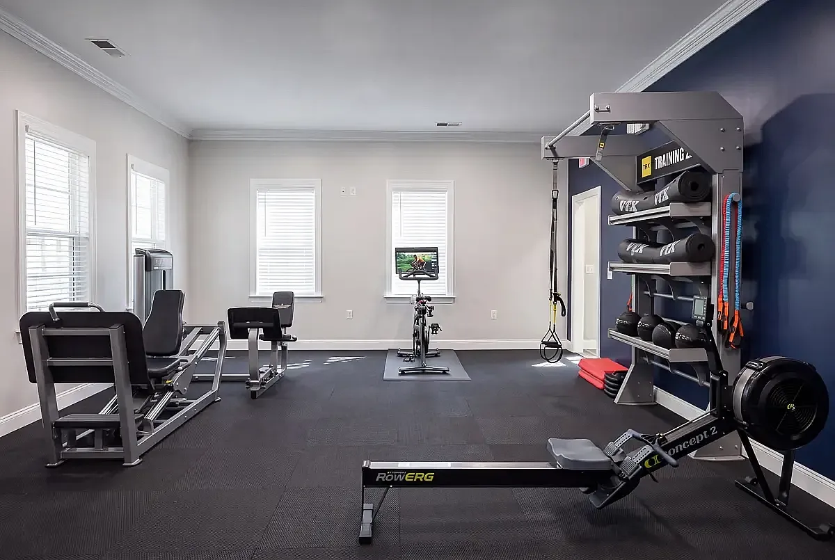 Modern fitness room with rowing machine, weight equipment, and ample natural light for an invigorating workout experience.