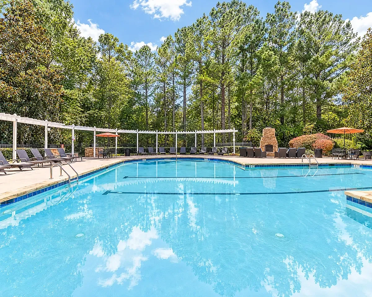 Inviting outdoor pool area with elegant lounge chairs and vibrant greenery, perfect for relaxation and leisure at Summer Park Apartments.