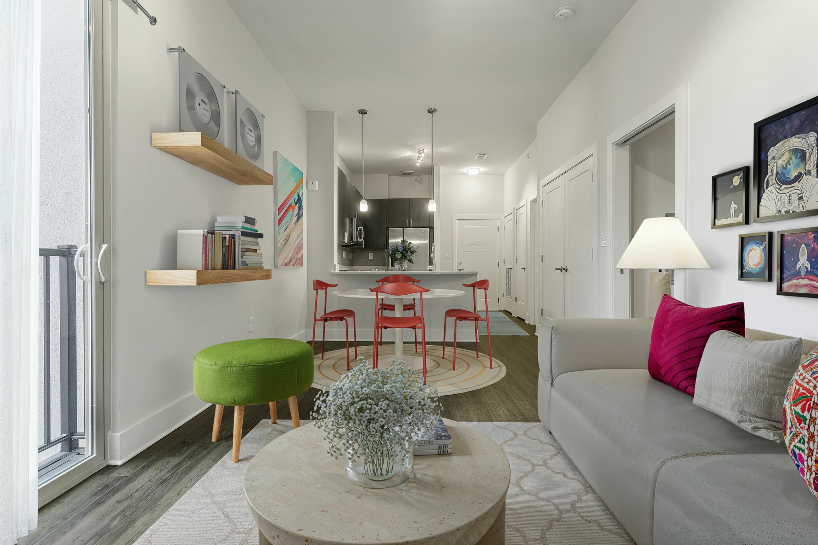 Modern living space with stylish decor, featuring a cozy sofa, vibrant artwork, and a sleek open-plan kitchen with red chairs in a 1 bedroom apartment in berry hill, TN