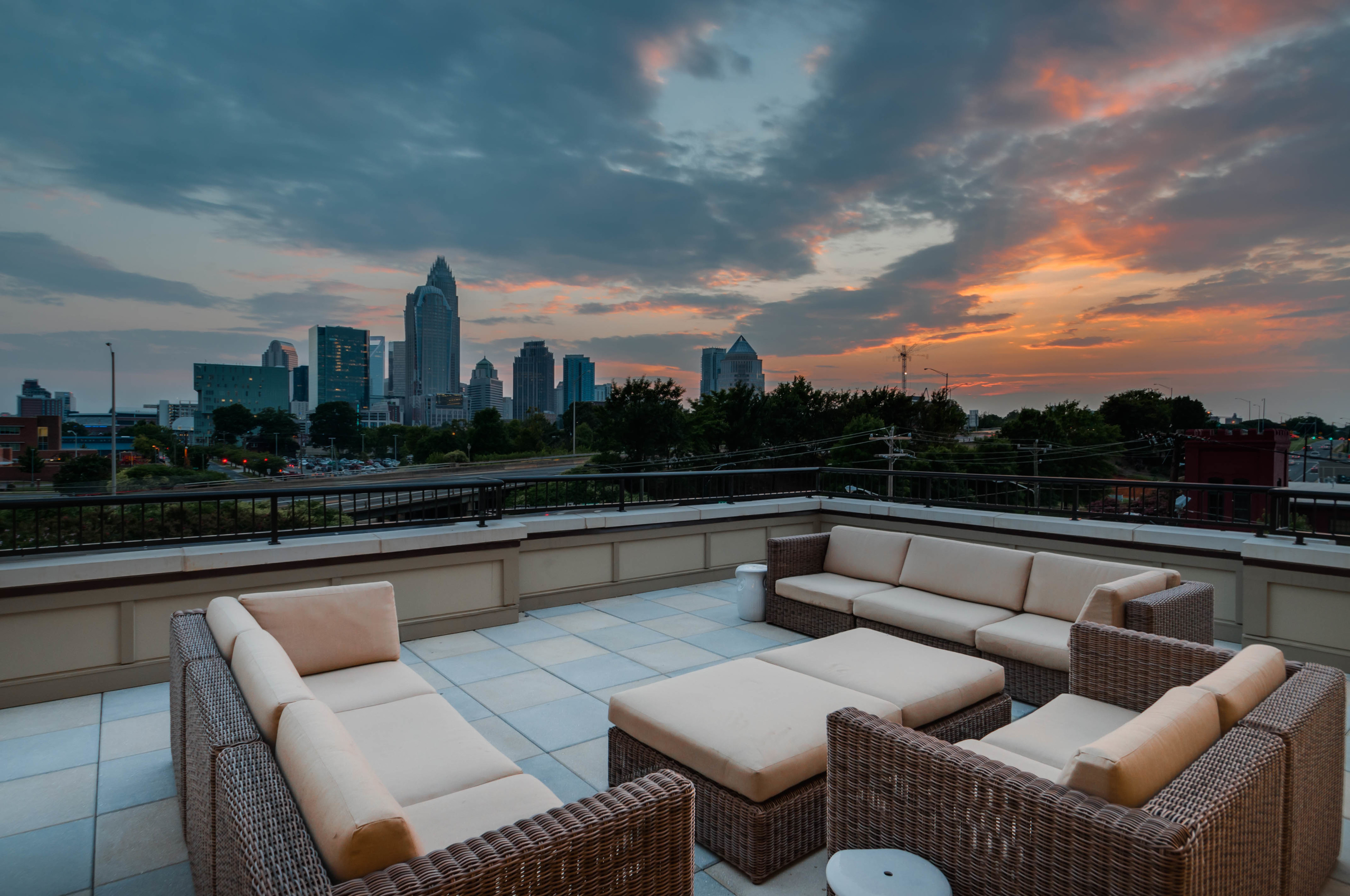View of Rooftop Lounge, Showing Outdoor Couches, Sky at Sunset, and Views of Uptown Charlotte at Alpha Mill Apartments