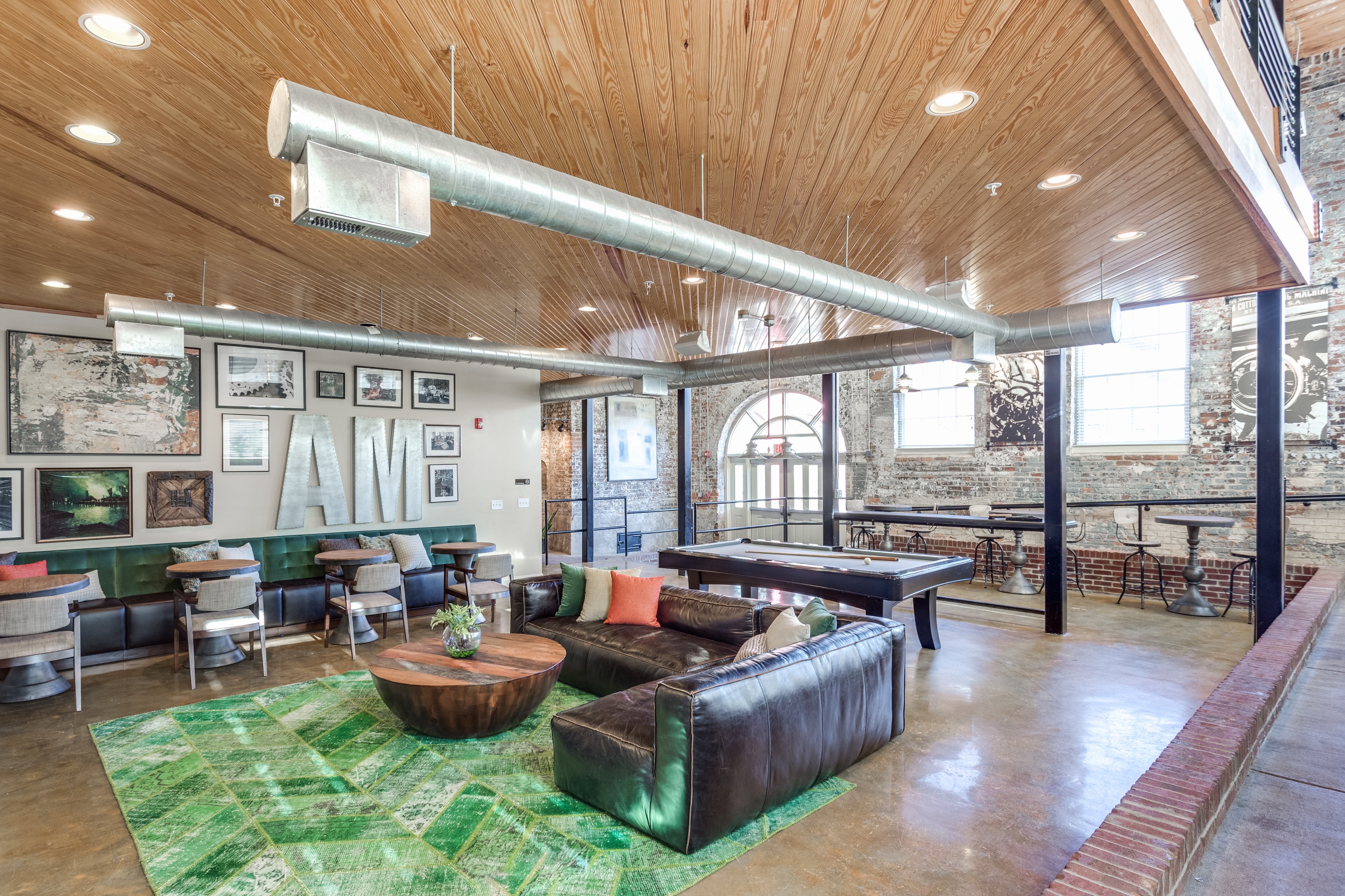 View of Resident Lounge, Showing Seating Area, Pool Table, and Mill Architecture at Alpha Mill Apartments
