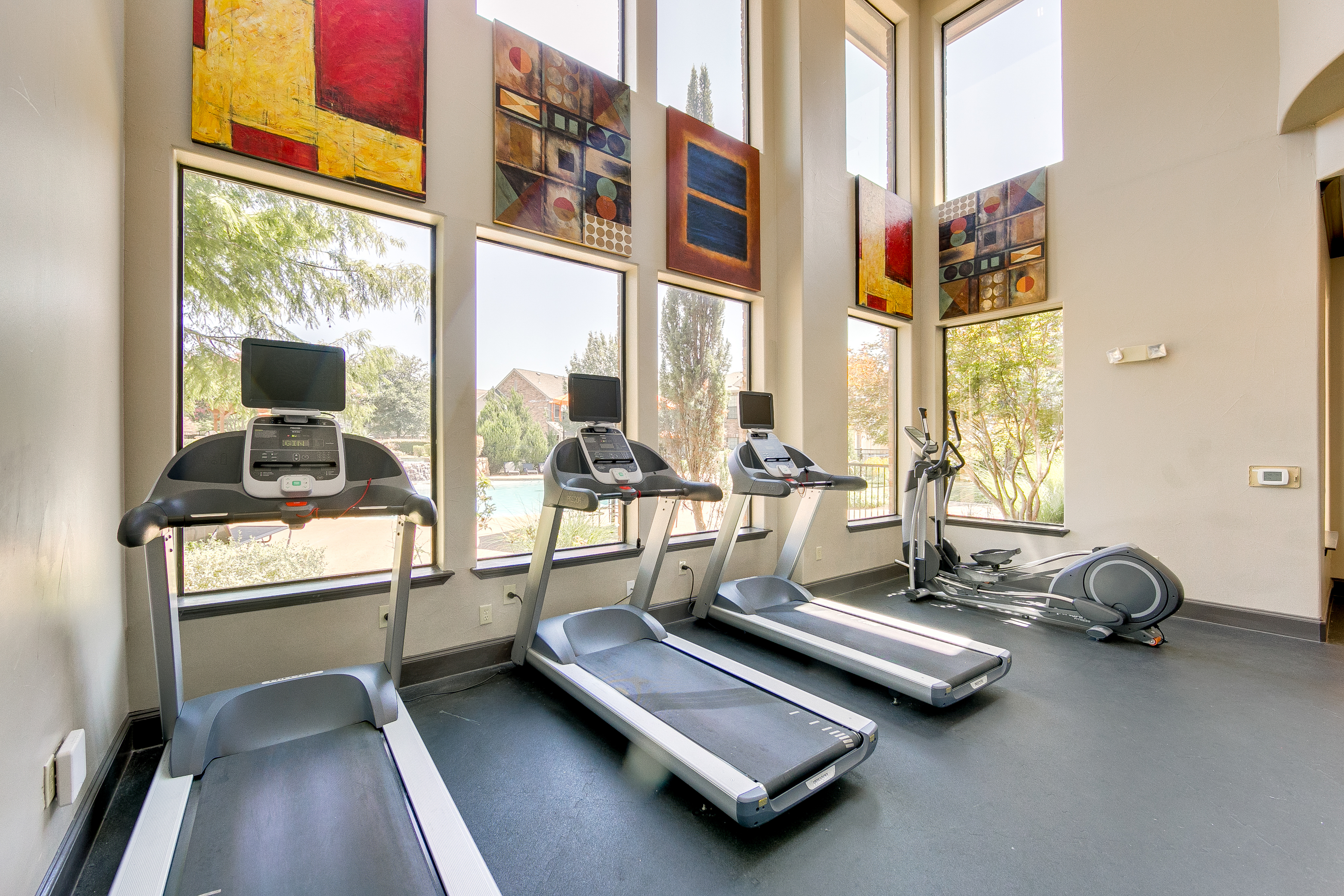 View of Fitness Center, Showing Cardio Equipment and Floor to Ceiling Windows at Enclave on Golden Triangle Apartments