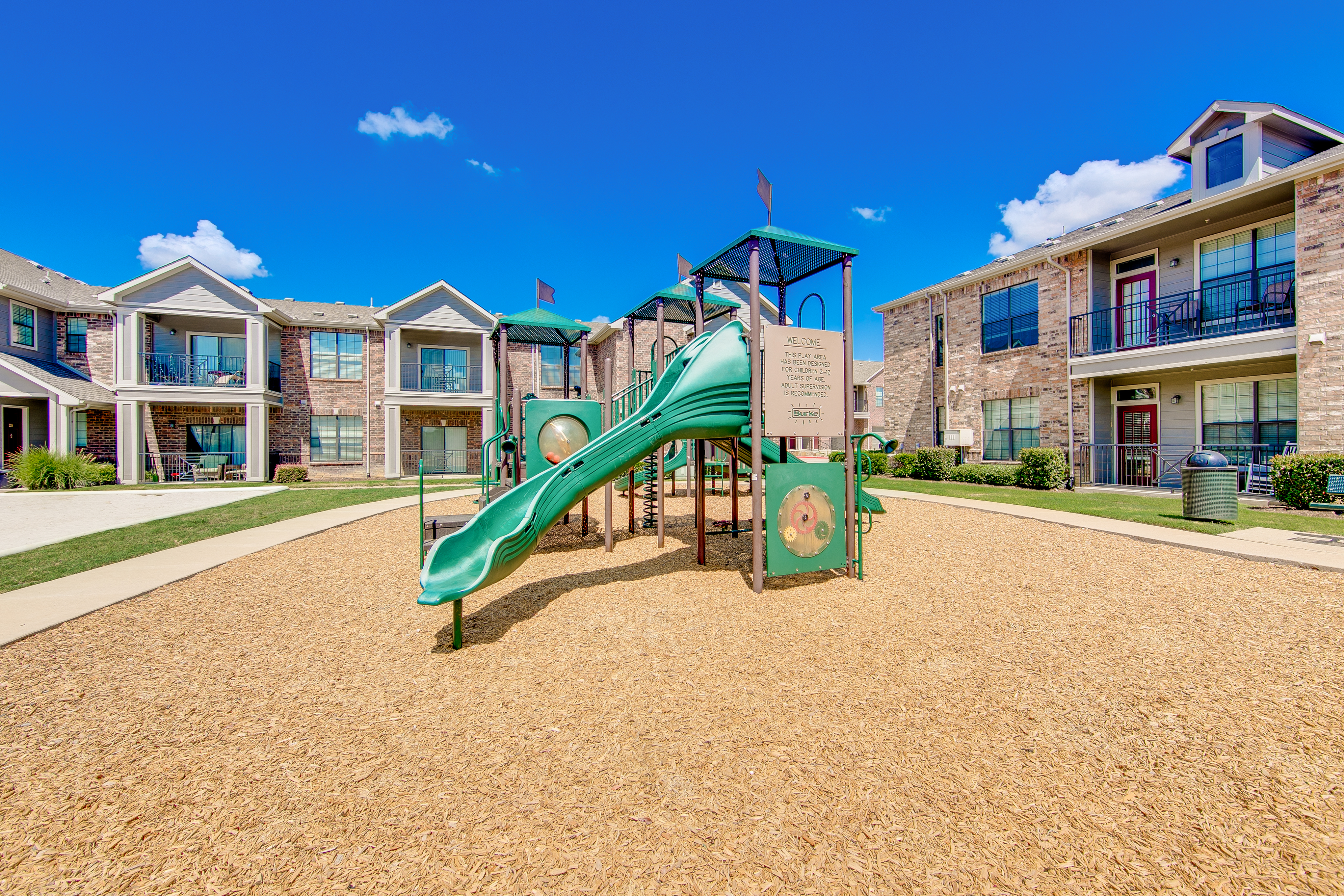 View of Playground, Showing Building Exteriors and Adjacent Sand Volleyball Court at Enclave on Golden Triangle Apartments