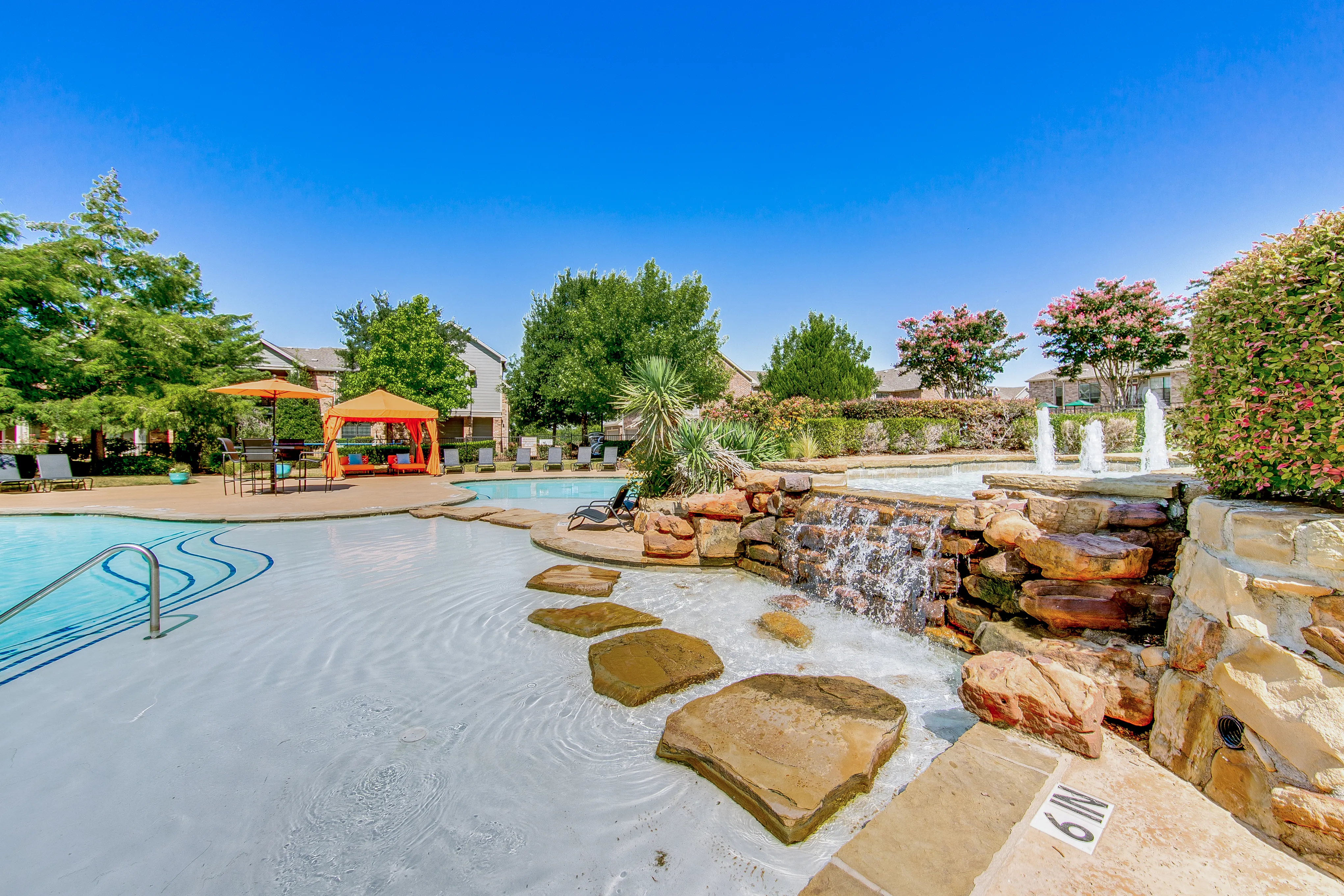 View of Resort Style Pool, Showing Sun Shelf, Waterfall, Seating, and Cabanas at Enclave on Golden Triangle Apartments