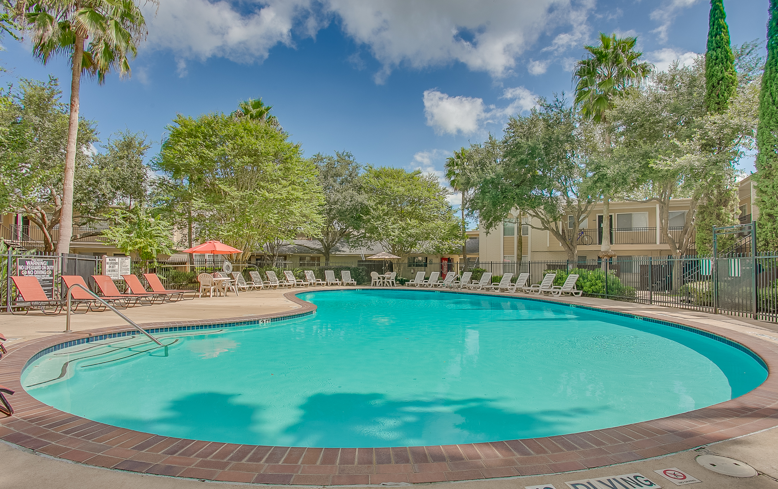 View of Pool Area, Showing Fenced-In Area, Picnic Area, and Loungers at The Regatta Apartments