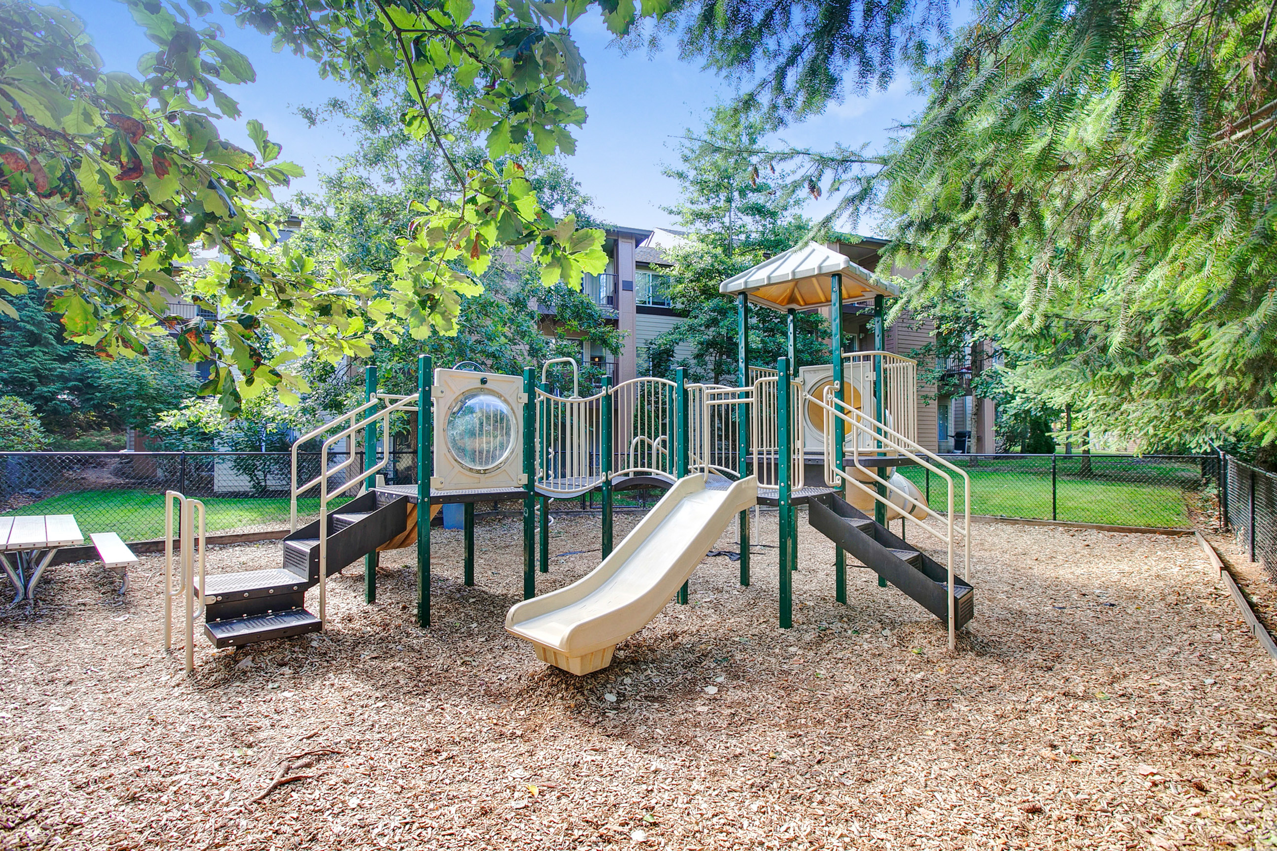View of Fenced Playground, Showing Equipment and Landscaping at Scott Mountain Apartments
