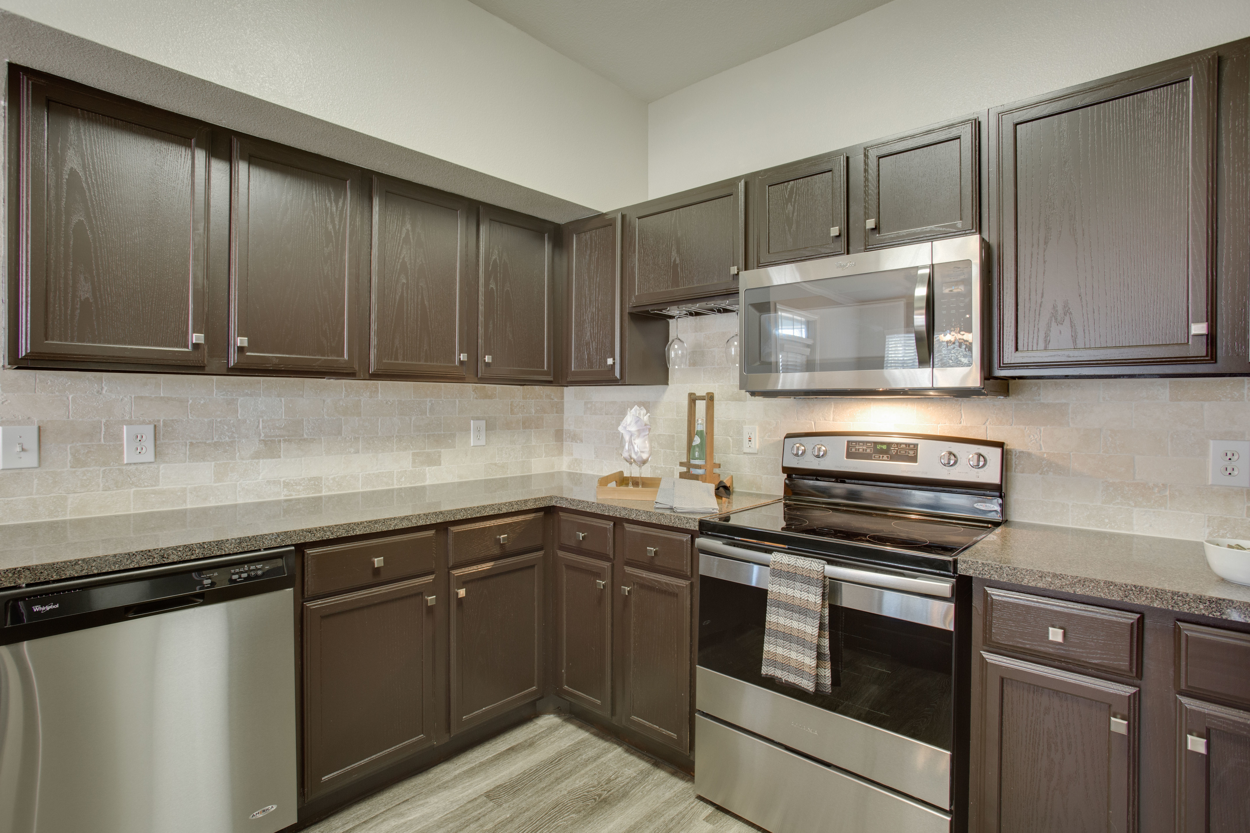 View of Kitchen with Plank-Wood Flooring and Stainless Steel Appliances and Raveneaux Apartments