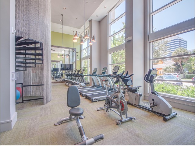 View of Fitness Center, Showing Bench, Cardio Machines, Window View, and TV at Cottonwood Bayview Apartments