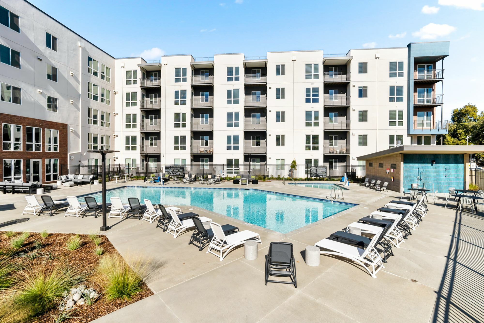Modern apartment complex with a spacious outdoor pool and lounging area.