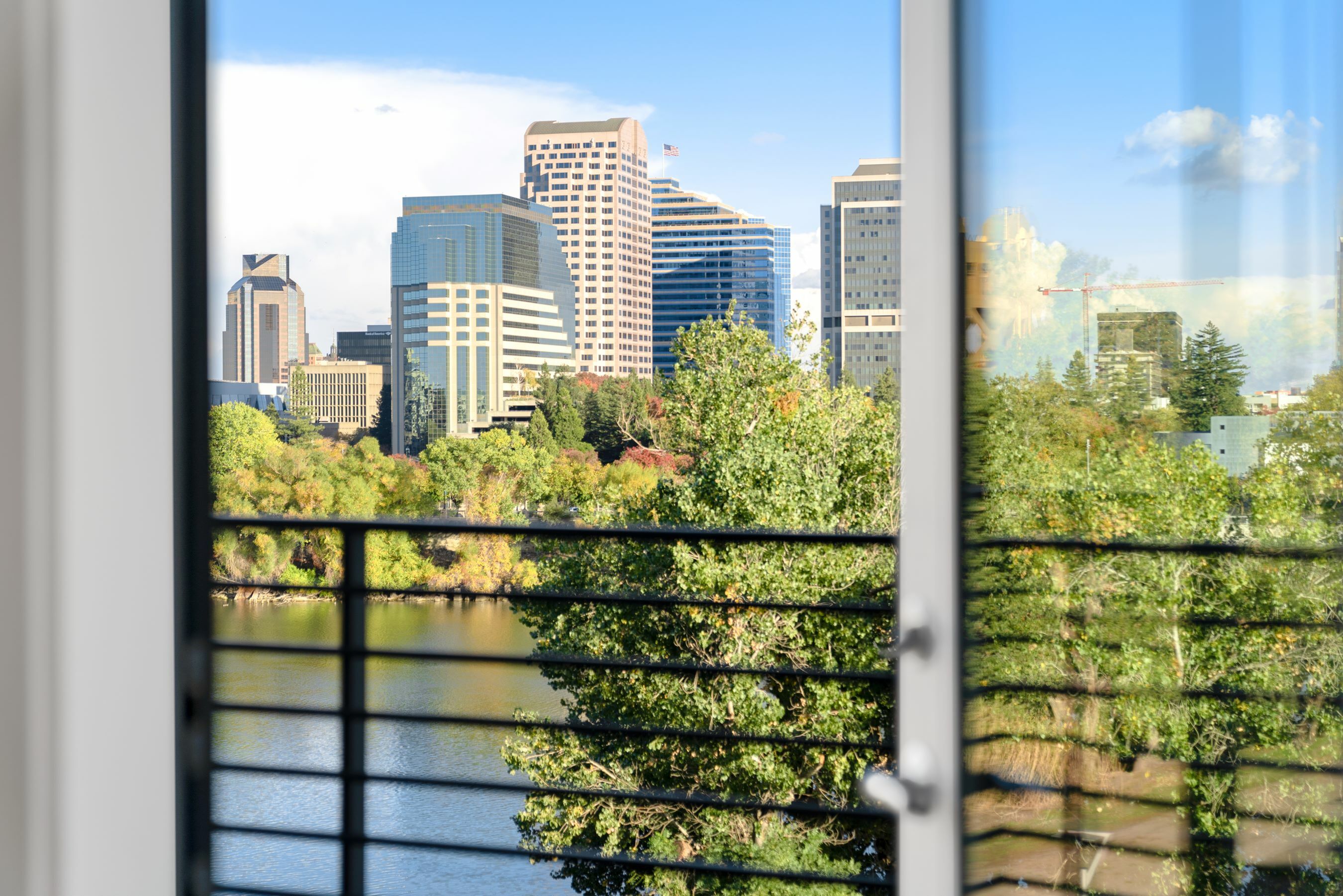 Breathtaking view from a modern apartment balcony overlooking a vibrant cityscape and tranquil river.