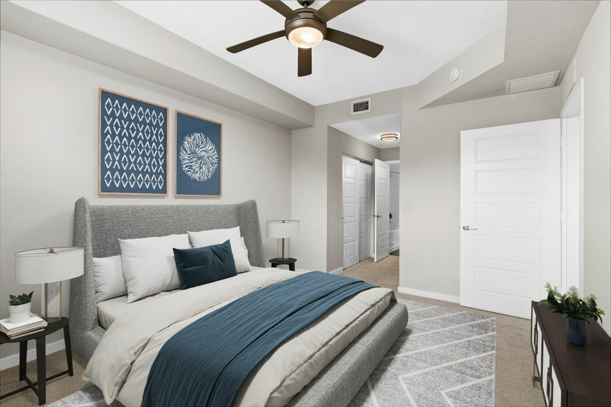 Inviting bedroom with modern gray and blue decor, featuring elegant artwork, sleek furniture, and a ceiling fan for a cozy, stylish atmosphere.