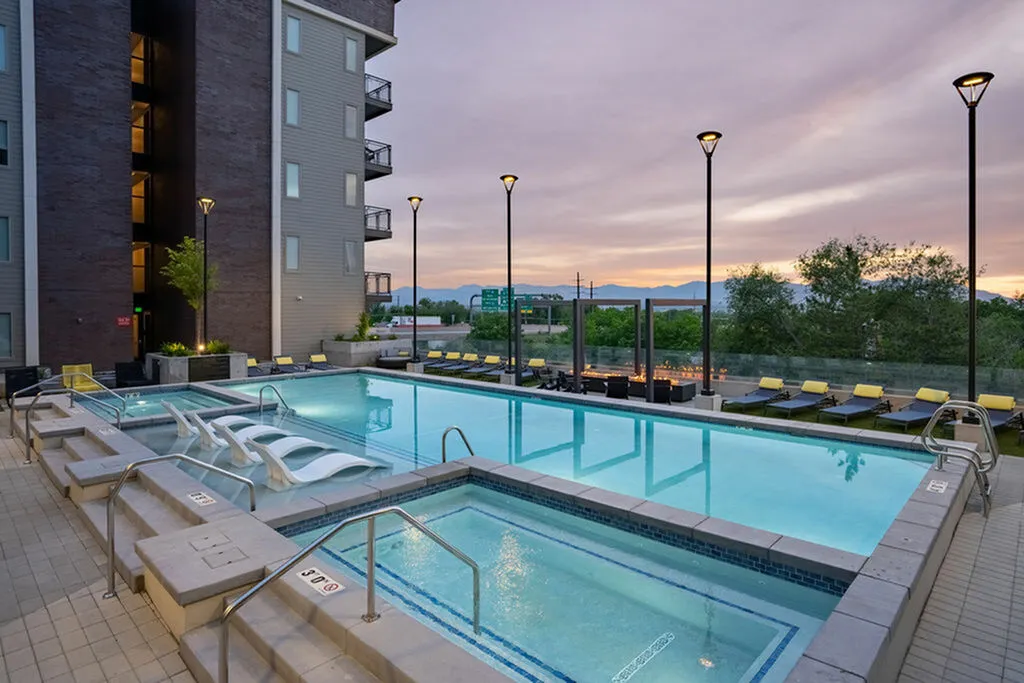 Luxurious apartment pool area with sleek loungers, ambient lighting, and breathtaking mountain views at sunset.