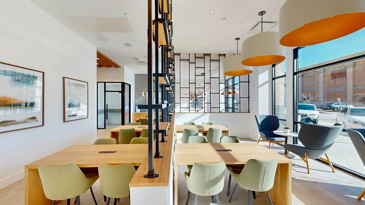 Bright and modern coworking space at Cottonwood Highland with elegant dining tables, chic light fixtures, and expansive windows offering plenty of natural light.