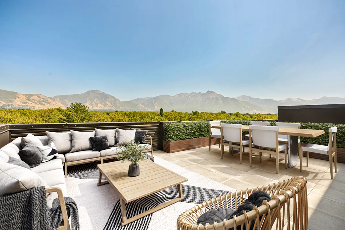 Luxurious rooftop terrace at Cottonwood Highland Apartments with comfortable seating, elegant dining area, and stunning mountain views under a clear blue sky.