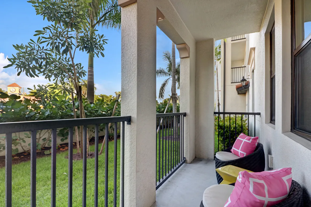 Inviting apartment balcony at Lighthouse Point Apartments with plush seating, vibrant pink cushions, and lush green views.