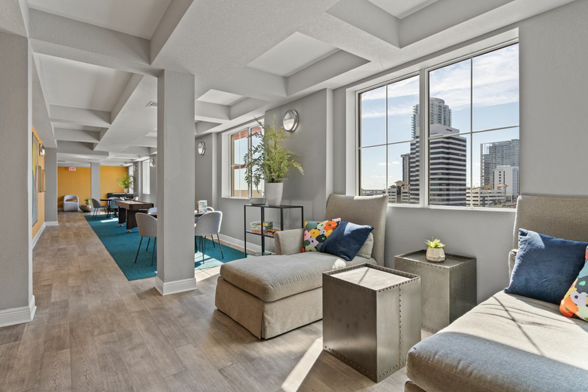 Bright and inviting modern lounge area with cozy seating, colorful decor, and expansive windows offering a stunning cityscape view in Downtown Saint Petersburg