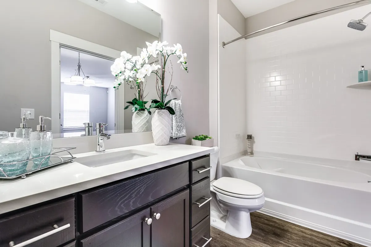 Elegant bathroom at Cottonwood Reserve Apartments with modern fixtures, featuring a spacious countertop, minimalist decor, and a chic bathtub.