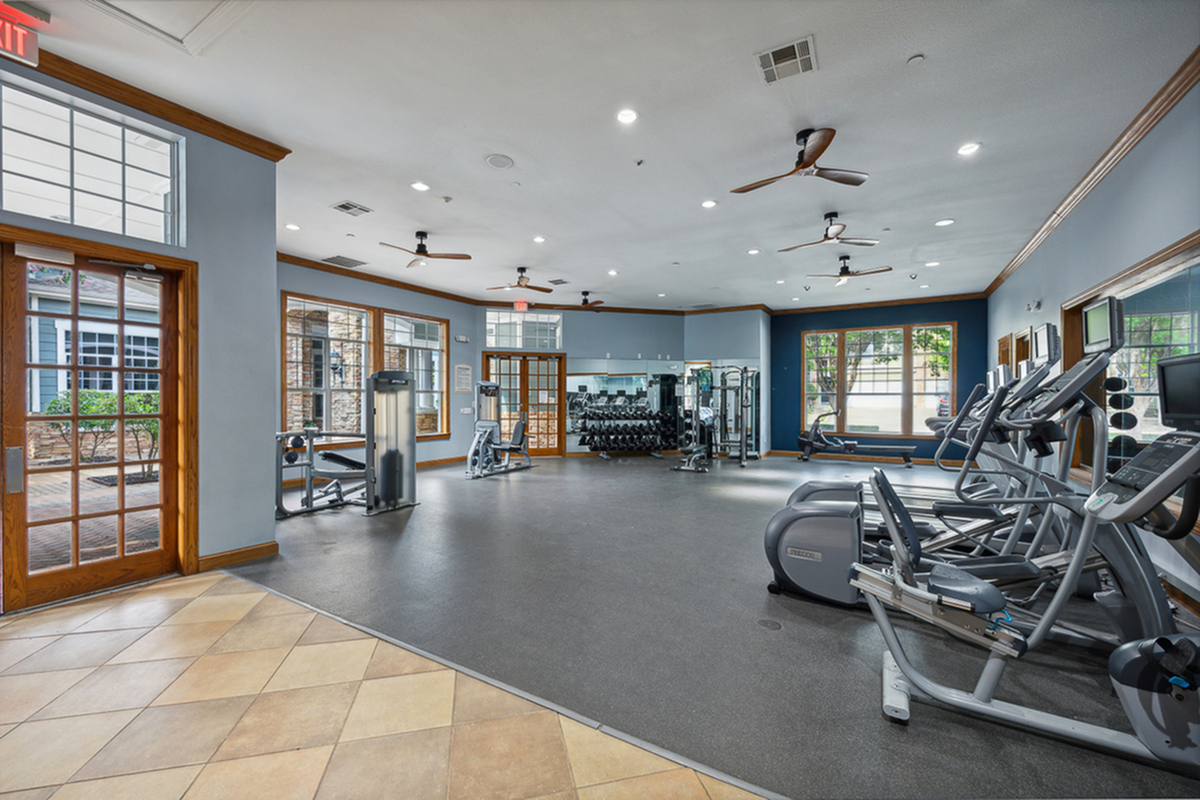Spacious and modern fitness center at Cottonwood Ridgeview Apartments with state-of-the-art equipment, large windows, and elegant design.