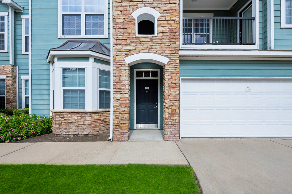Charming apartment exterior at Cottonwood Ridgeview with a stone facade, vibrant blue siding, and a welcoming front entrance.