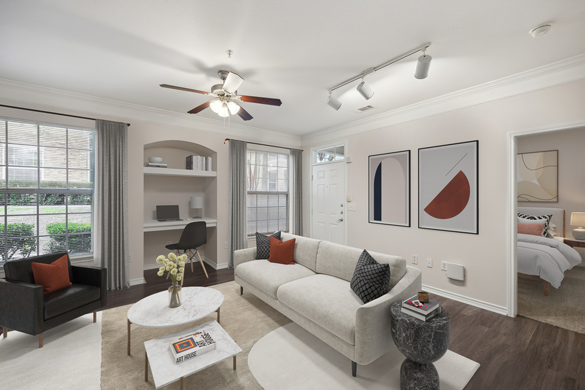 Chic living room at Cottonwood Ridgeview Apartments with modern decor, featuring a cozy sofa, stylish coffee table, and built-in workspace with ample natural light.