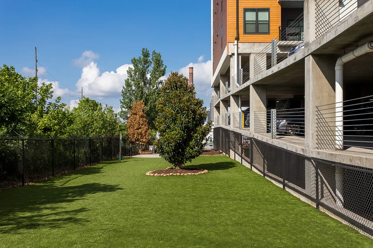 Inviting dog park at Cottonwood Westside adjacent to a modern building, perfect for relaxation and outdoor activities.