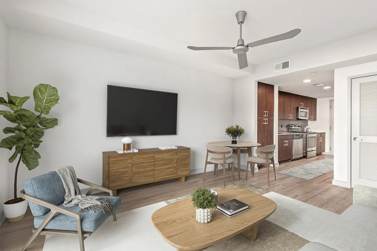 Modern open-plan living area at Cottonwood Westside Apartments featuring sleek wooden furniture, a stylish dining set, and a well-equipped kitchen with stainless steel appliances.