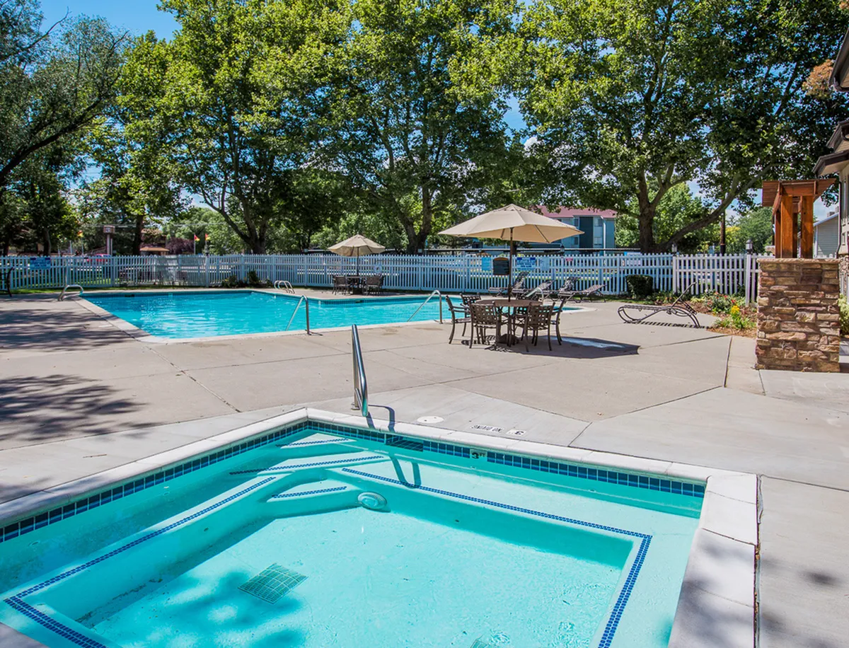 Inviting outdoor pool area at Fox Point in Old Farm Apartments with a relaxing hot tub, surrounded by lush greenery and comfy seating, perfect for sunny leisure.