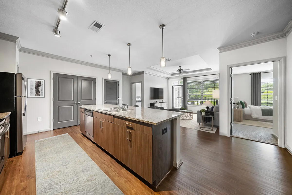 Bright and modern open-concept kitchen at Heights at Meridian Apartments and living area with hardwood floors, granite countertops, and large windows overlooking greenery.