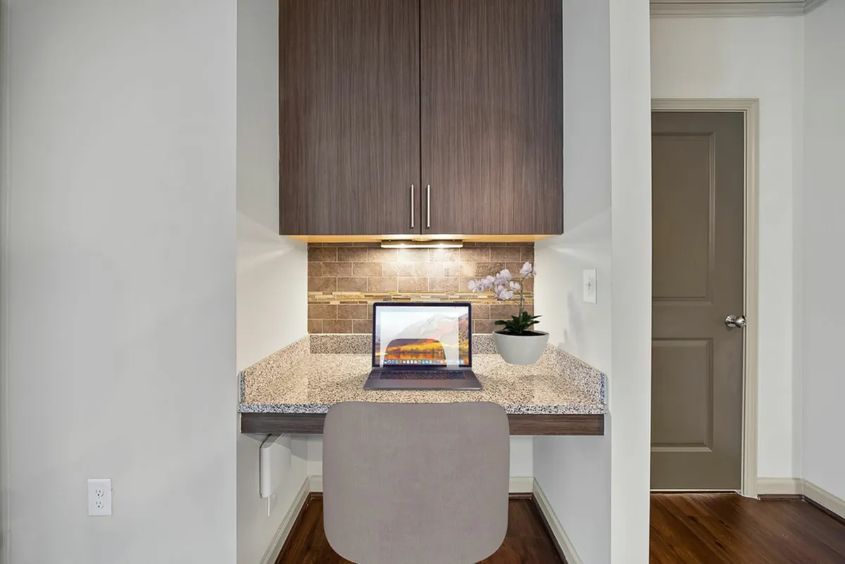 Modern compact workspace at Heights at Meridian Apartments featuring a sleek granite desk, elegant cabinetry, and warm lighting, ideal for productivity in stylish surroundings.
