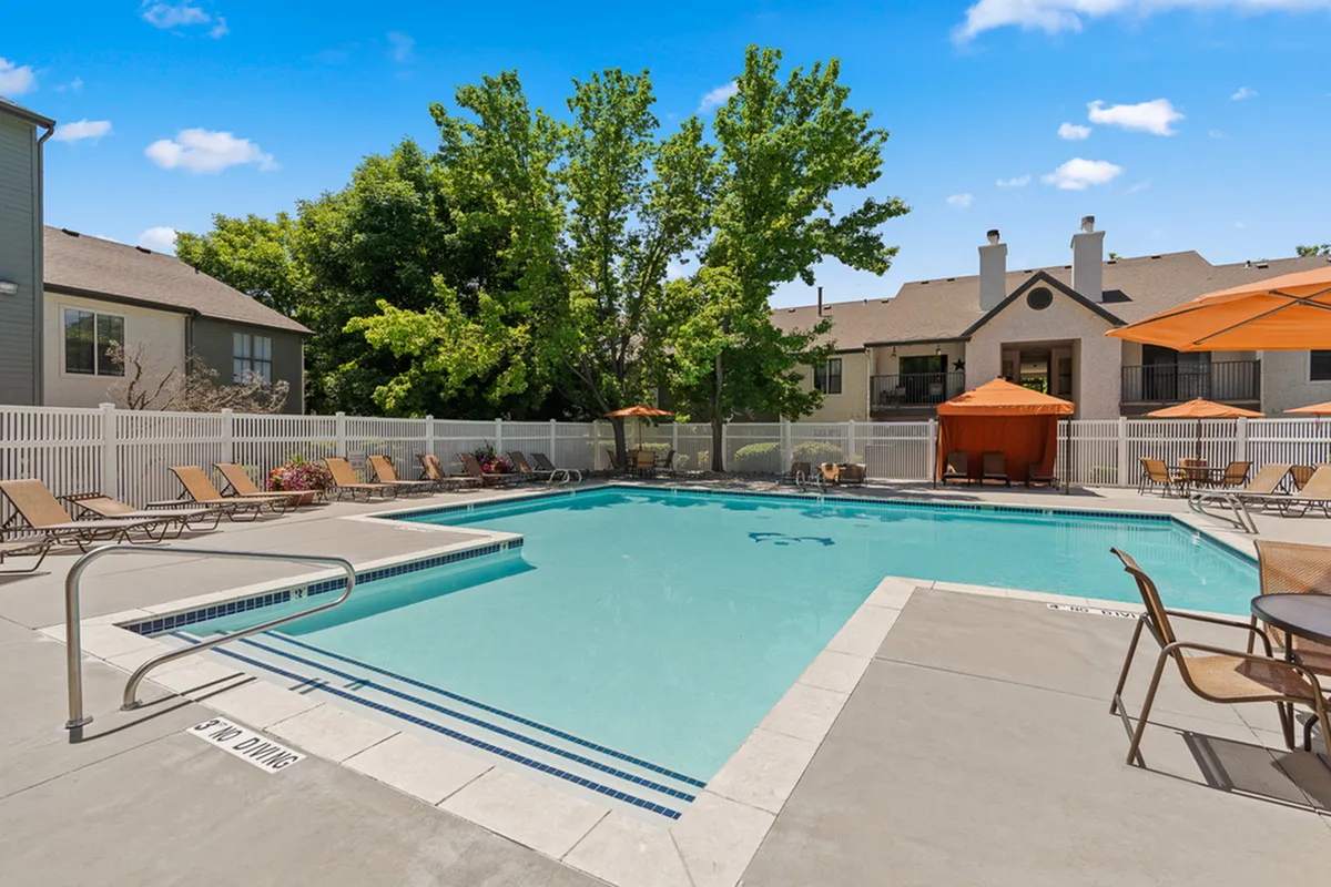 Luxurious apartment community with a sparkling pool, sun loungers, and shaded cabanas, offering a perfect outdoor retreat.