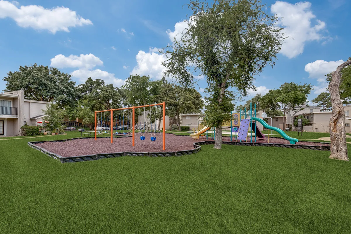Inviting community playground surrounded by lush greenery, featuring swings and a vibrant slide perfect for family fun.