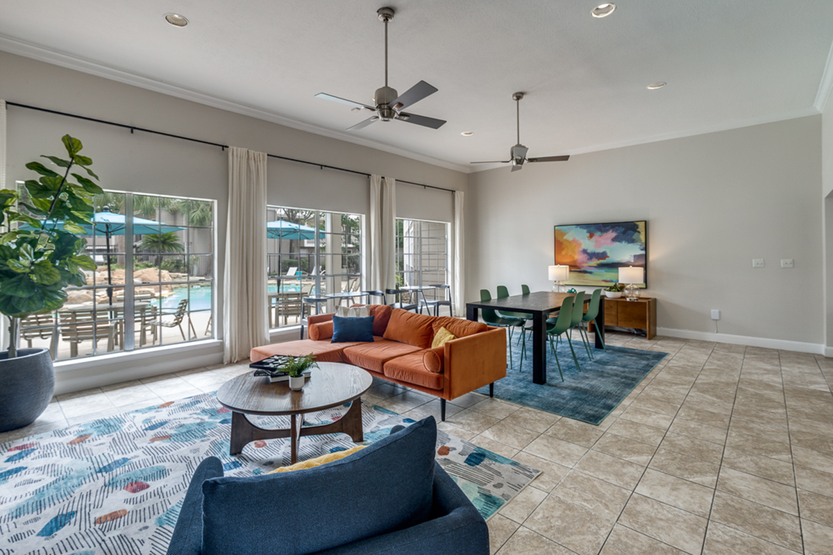 Elegant open-plan living space with modern furnishings, large windows overlooking a pool, and stylish dining area.