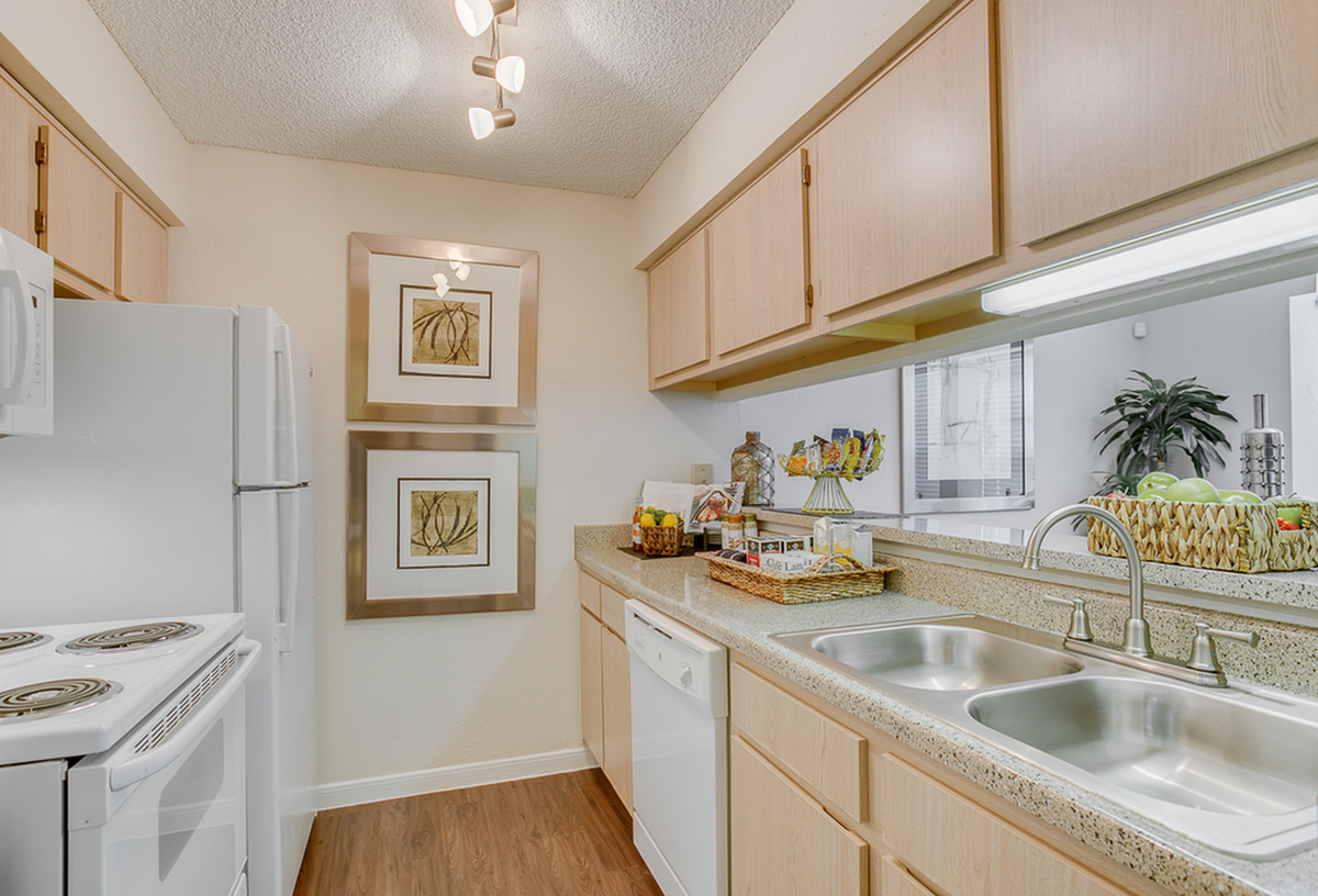 Inviting kitchen with sleek countertops, double sink, and ample wooden cabinetry, accented by modern lighting and decorative artwork.