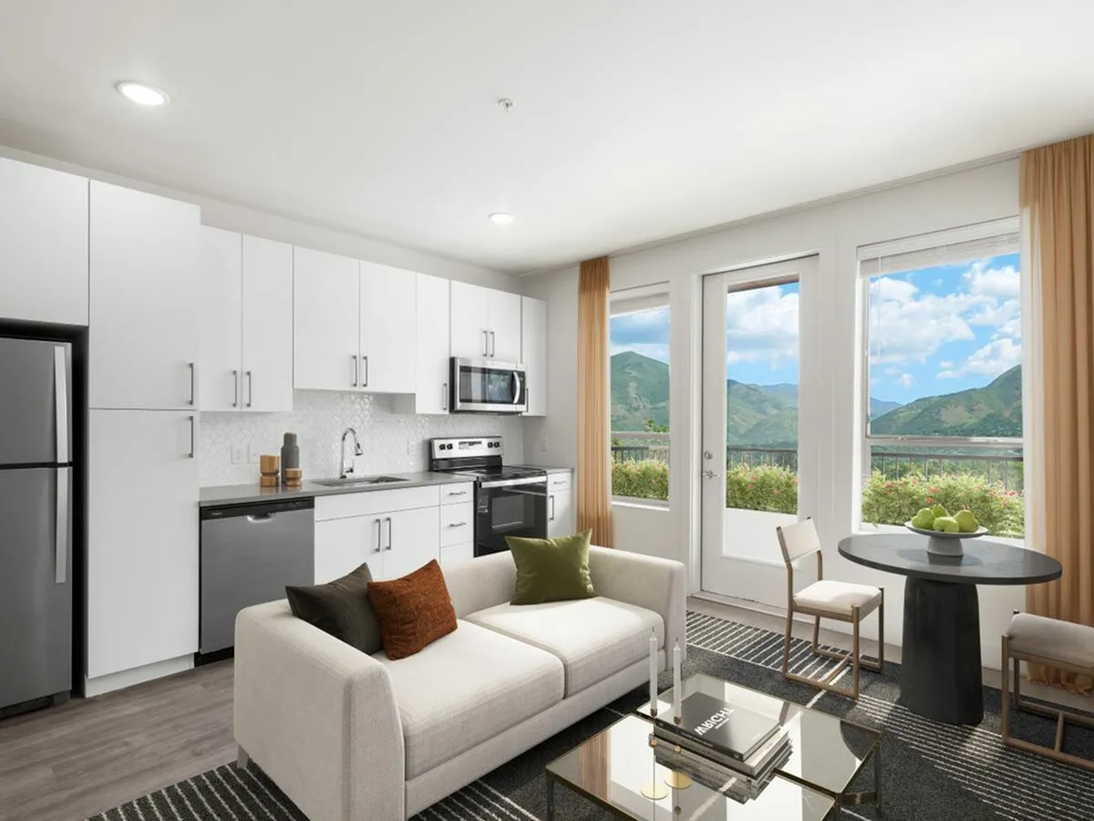 Modern open-concept kitchen and living room with sleek appliances, cozy sofa, and scenic mountain views from bright windows at The Richmond Apartments in SLC