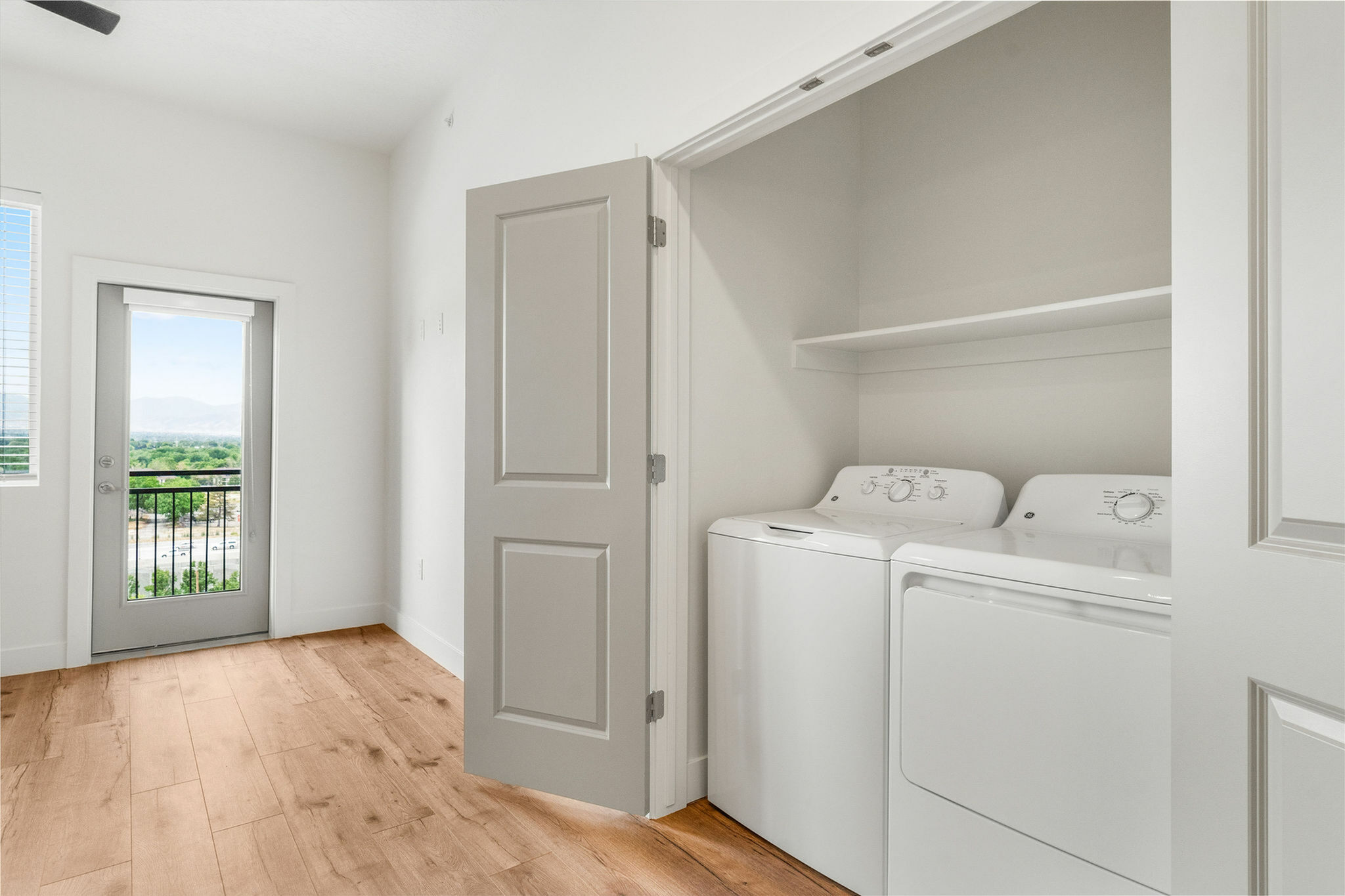 Bright, modern laundry room with sleek appliances and inspiring outdoor view from the balcony at Current Apartments in Murray Utah