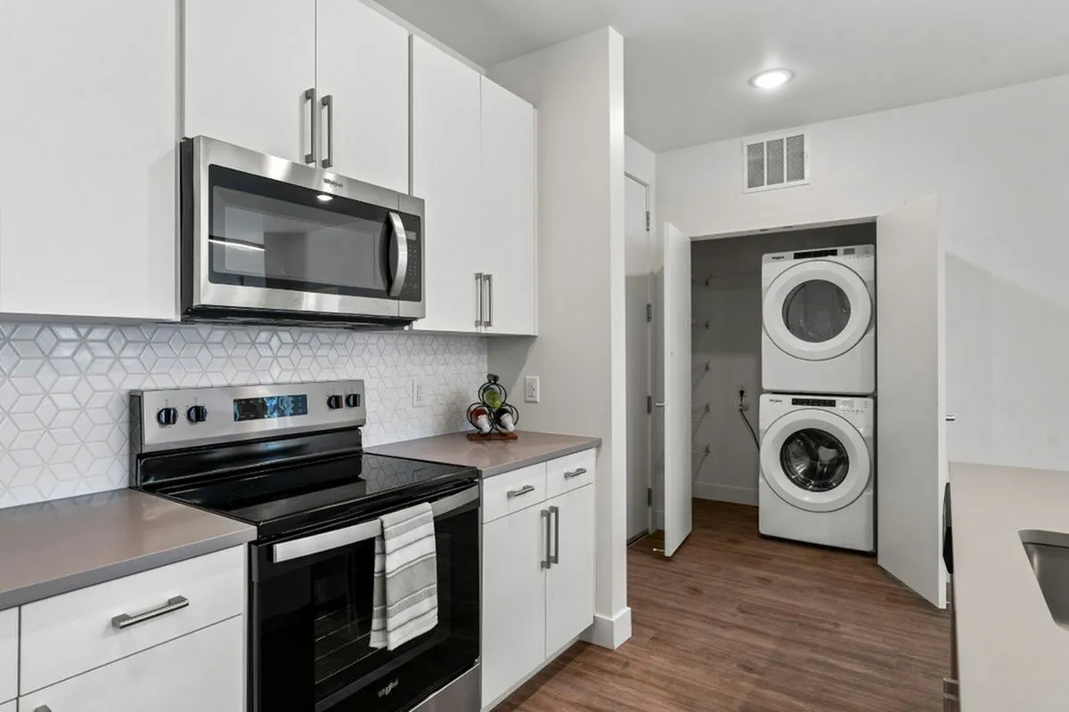 Modern kitchen with sleek stainless, and an efficient stacked washer and dryer in a stylish apartment setting at The Richmond Apartments in SLC