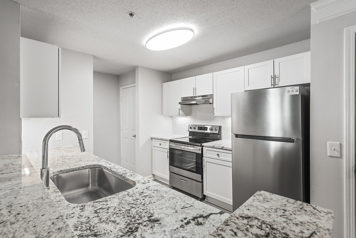 Modern kitchen with sleek stainless steel appliances, elegant marble countertops, and bright white cabinetry.